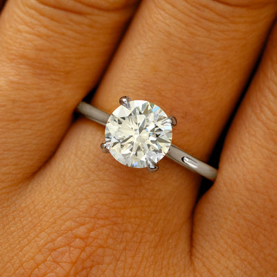 A solid 950 platinum Round Lab Diamond Cathedral Set Ring on a model's finger