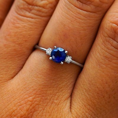 Close up view of a model's hand wearing a 950 platinum three stone sapphire ring