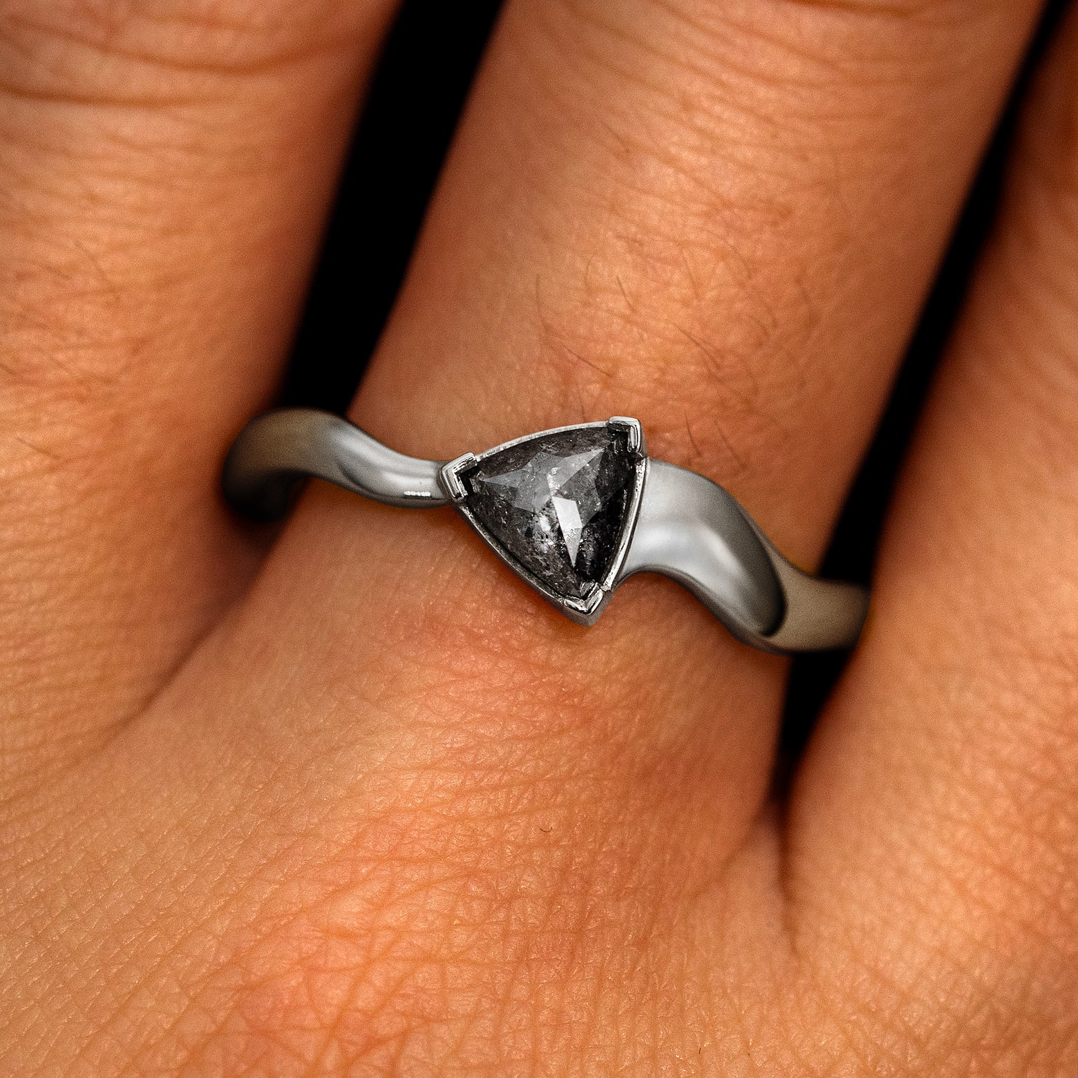 A model's hand wearing a 950 platinum Trillion Salt and Pepper Diamond Wavy Ring