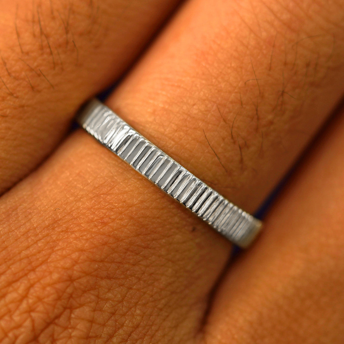 Close up view of a model's fingers wearing a 950 Platinum Edge Band