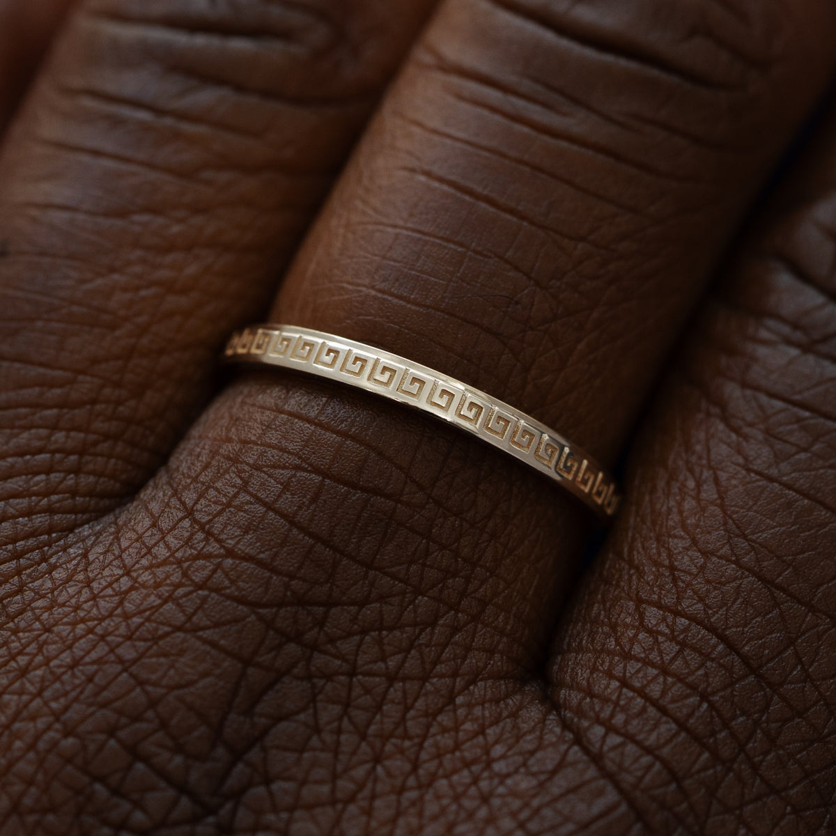 Close up view of a model wearing a solid 14k champagne gold geometric grass band