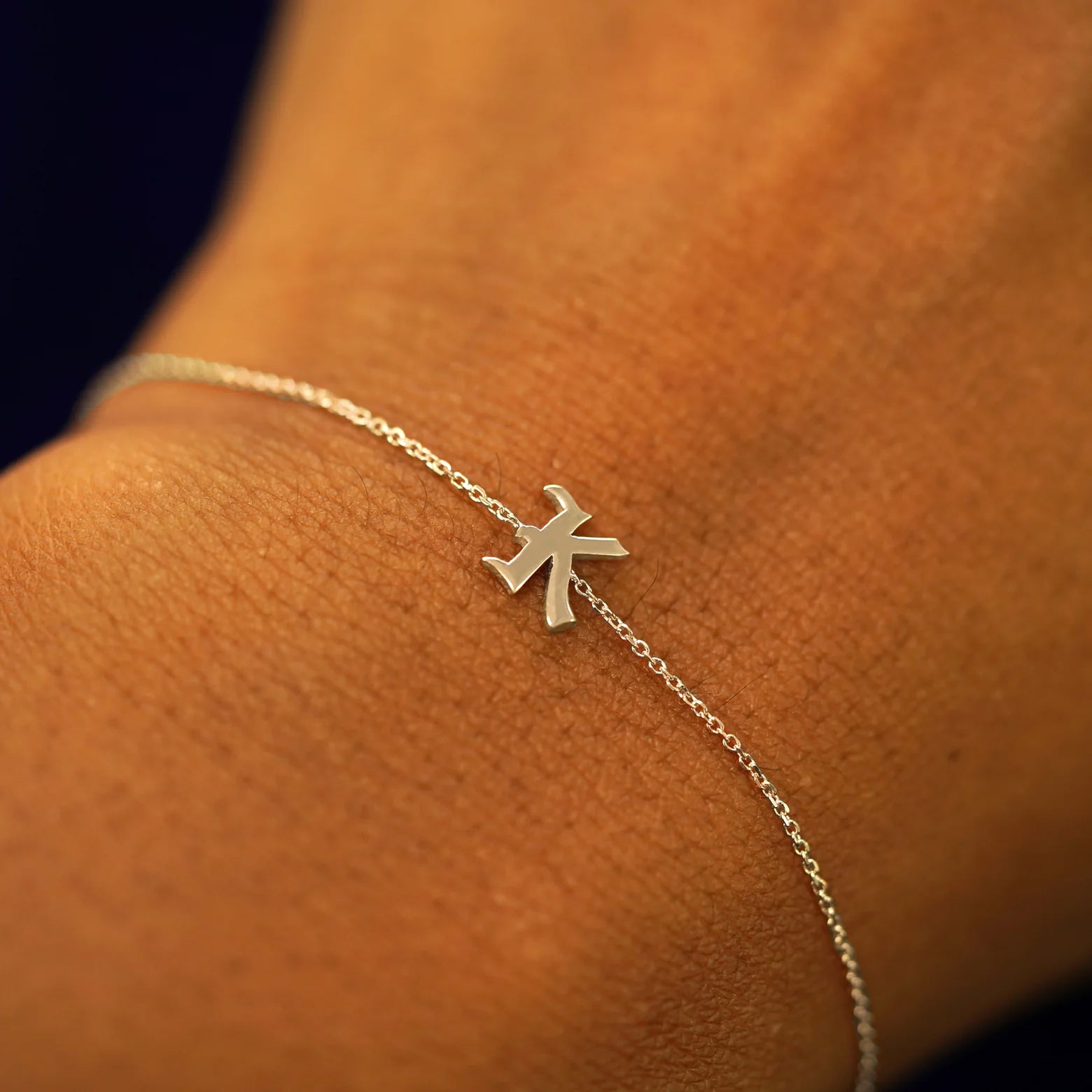 A model's wrist wearing a 14k solid champagne gold Initial Bracelet in the letter K