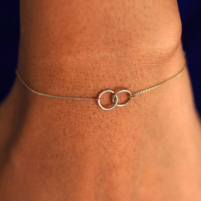 A model's wrist wearing a solid champagne gold Mini Bound Together Bracelet