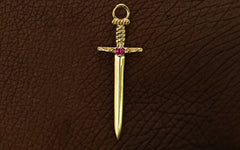 A yellow gold ruby Sword Charm resting on the back of a model's hand