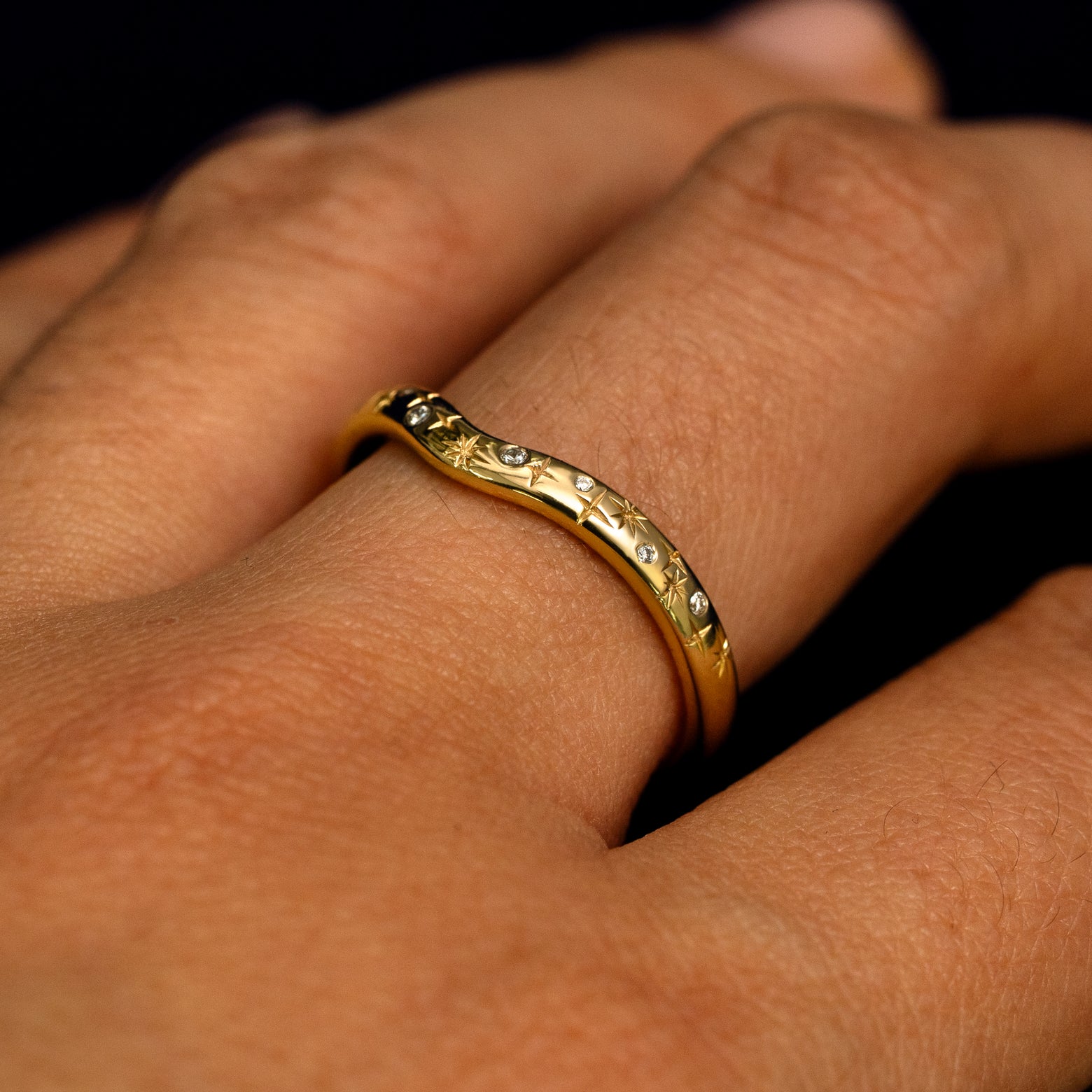 Side view of a Curvy Chevron Diamond Stars Band on a model's finger