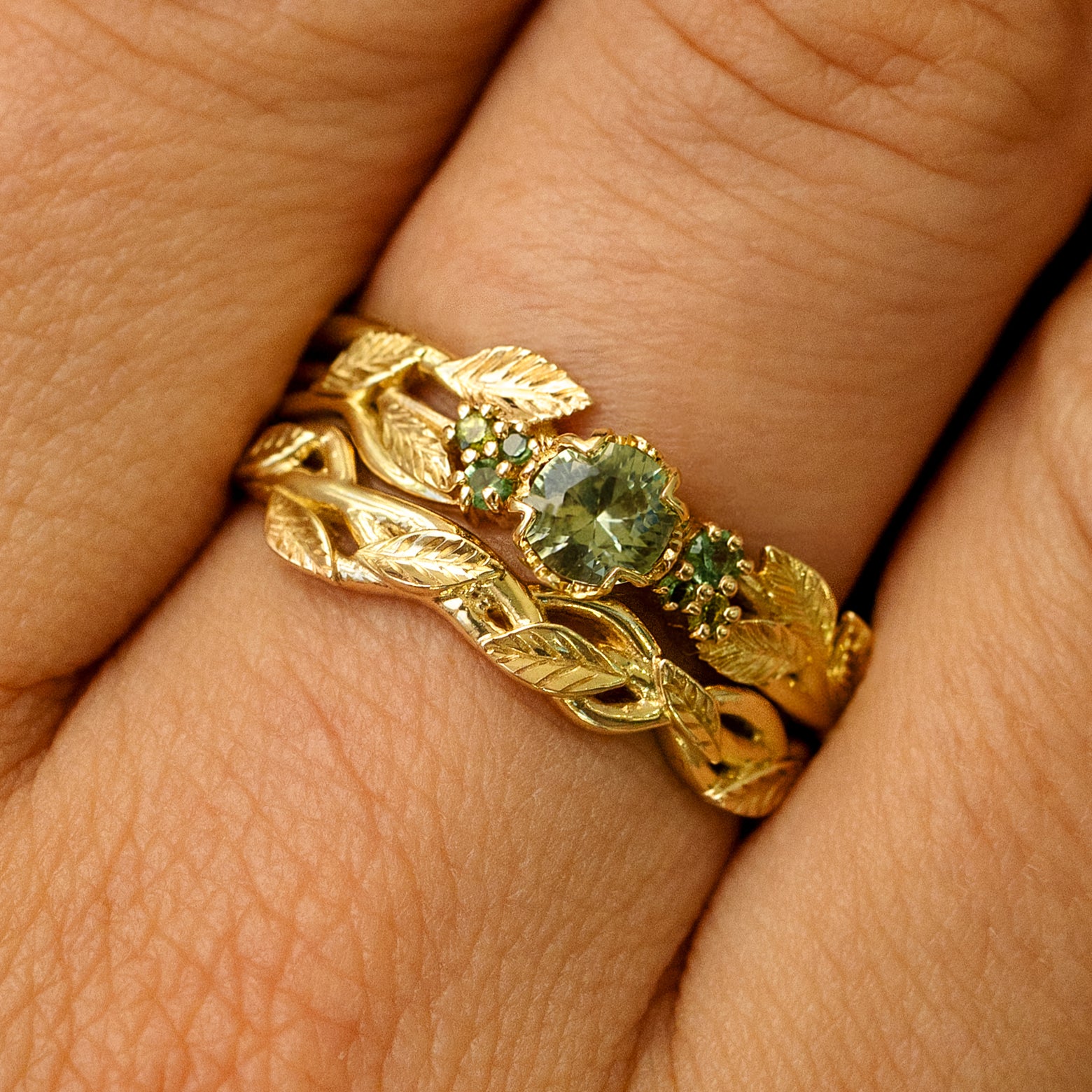 A Green Sapphires Leaves and Vines Ring stacked with a Braided Leaves and Vines Ring on a models finger