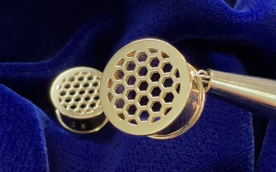 A pair of 14k yellow gold gauges with honeycomb detailing on a blue cloth background