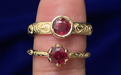 Two 14k gold ruby rings with leaf details, one with a thin band and prong setting, one with a thicker band and bezel setting