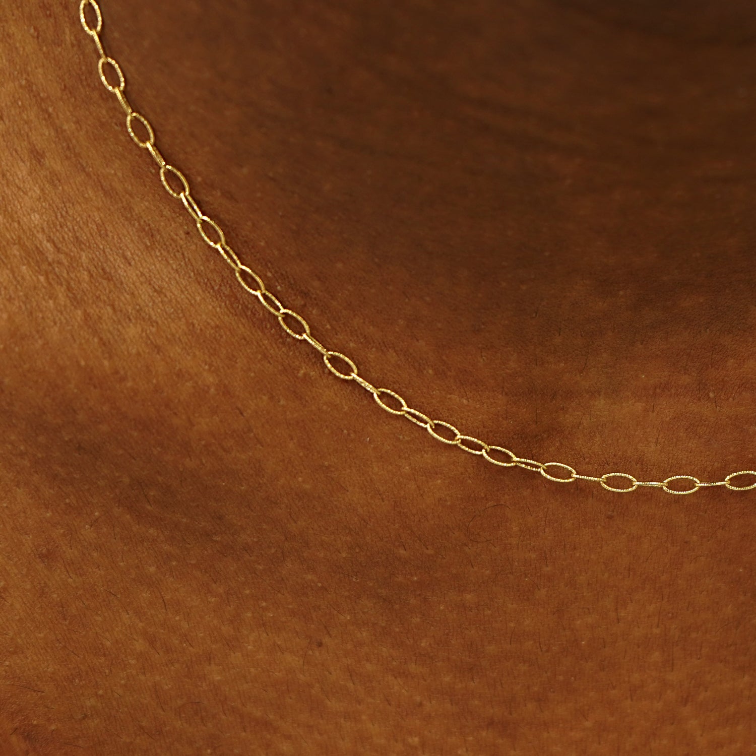 Close up view of a model's neck wearing a 14k yellow gold Veren Chain