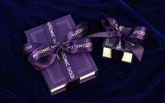 An Automic Gold gift box and ring box wrapped in Automic Gold branded ribbon