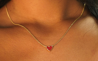 Close up view of a model's neck wearing a yellow gold red Enamel Heart Necklace