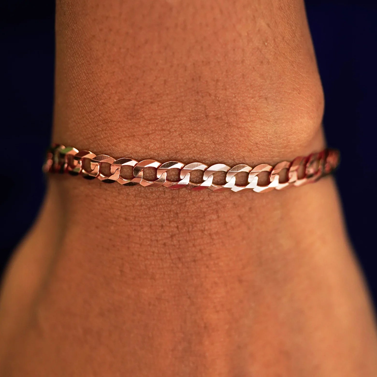A model's wrist wearing a rose gold Curb Chain Bracelet