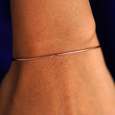 Close up view of a model's wrist wearing a rose gold Line Bangle Bracelet