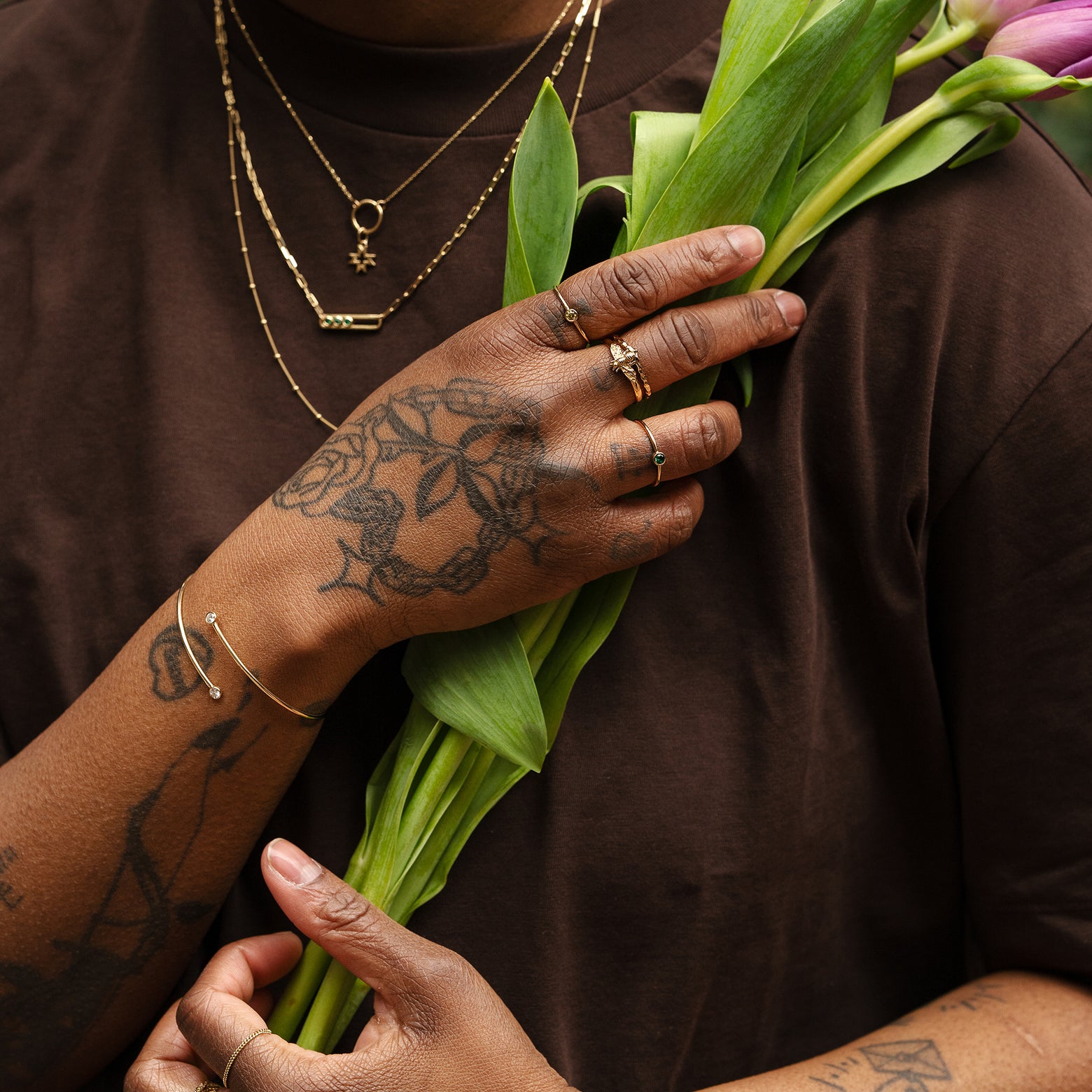 A model holding flowers and wearing r Automic Gold jewelry