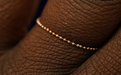 A yellow gold Bead Chain Ring on a model's finger