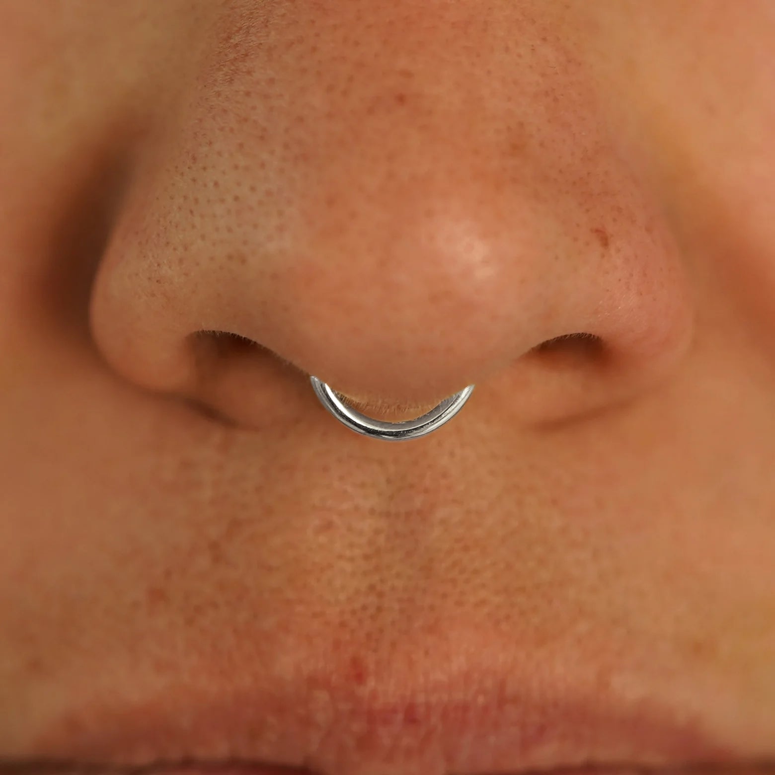Close up view of a model's nose wearing a 14k white gold Small Seamless Huggie Hoop in a septum piercing