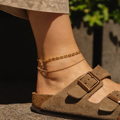 A model wearing puffy mariner anklet and rope anklet in 14k yellow gold 