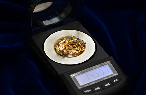 A pile of gold jewelry being weighed on a scale