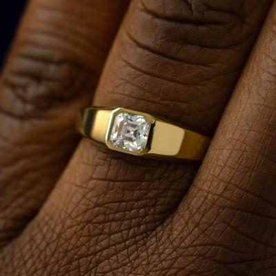 Close up view of a models hand wearing a solid gold asscher lab moissanite ring