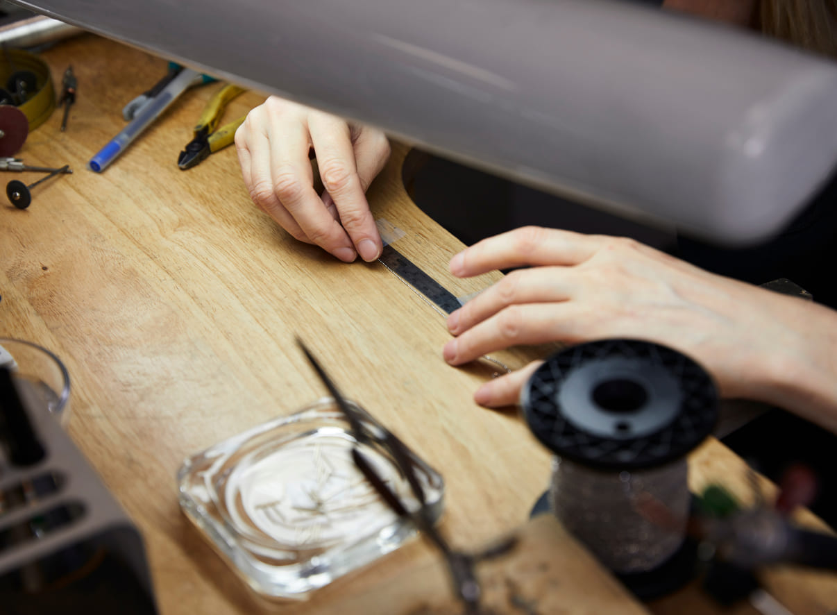 An Automic Gold jeweler hand-crafting solid gold jewelry at a work bench