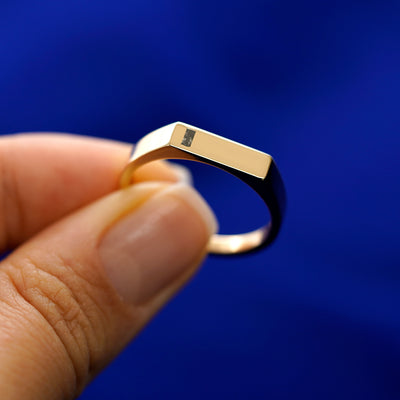 A model holding a baguette salt and pepper diamond rectangular signet ring tilted to show the setting of the stone