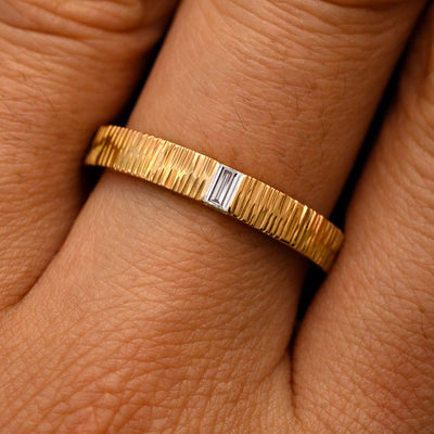 Close up view of a model's fingers wearing a 14k yellow gold Baguette Lab Diamond Wood Band