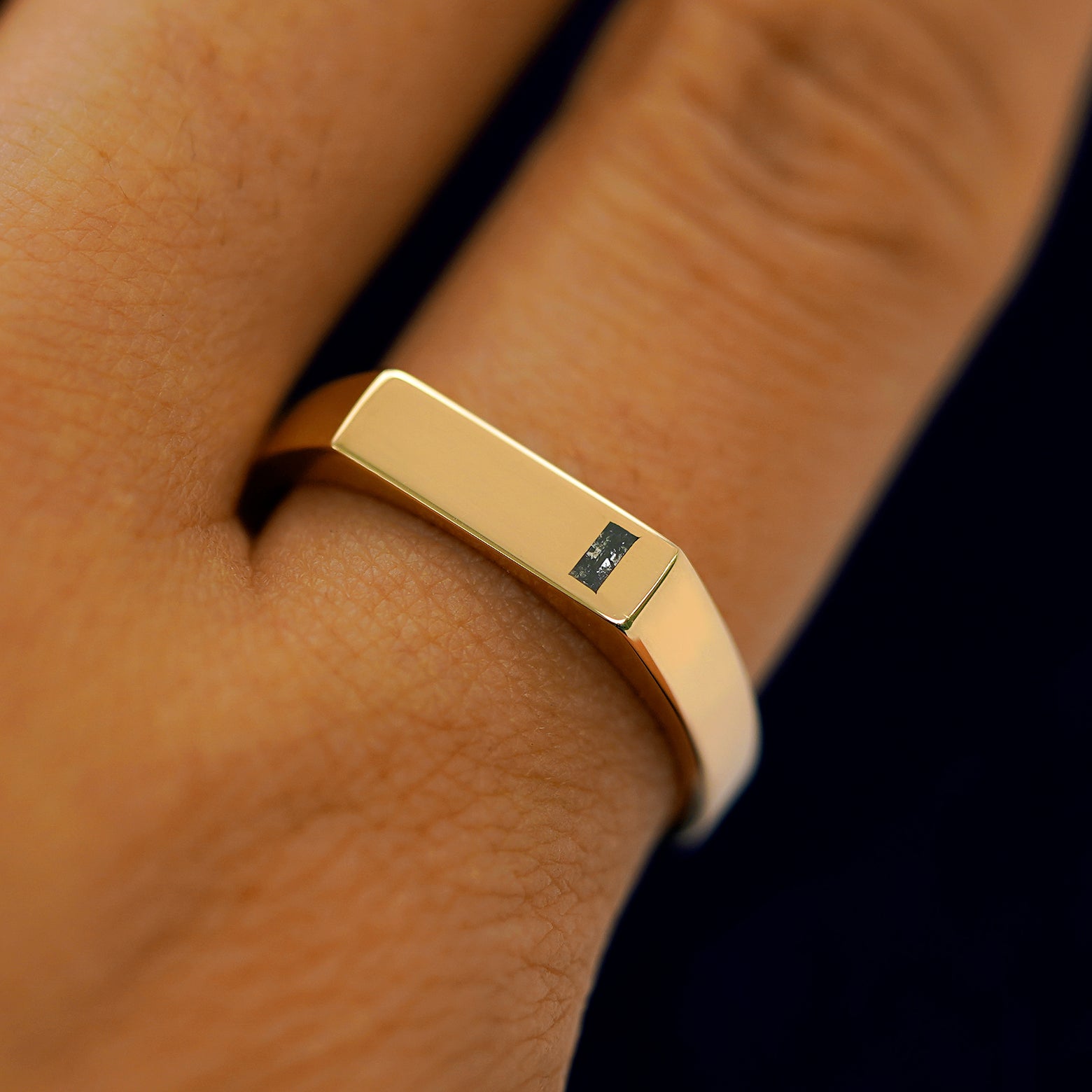 A model wearing a yellow gold baguette salt and pepper diamond rectangular signet ring as a pinky ring