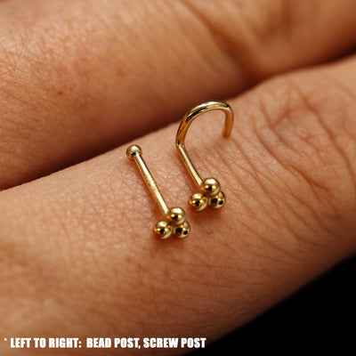 Close up view of a single two Ball Trio Nose Studs with different backings resting on the back on a model's hand