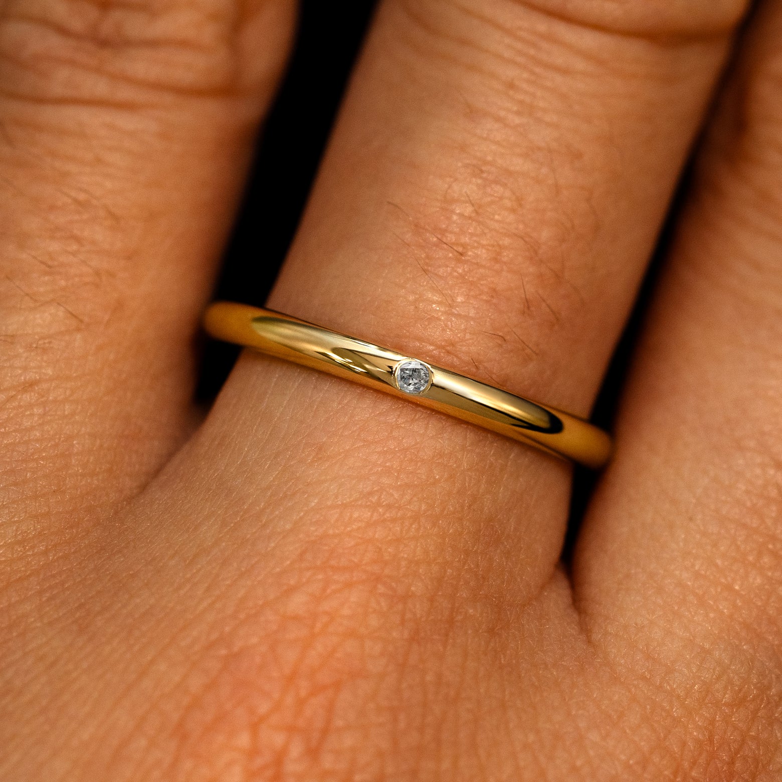 A 14k yellow gold Flush Set Sal and pepper Round Diamond Ring on a model's finger