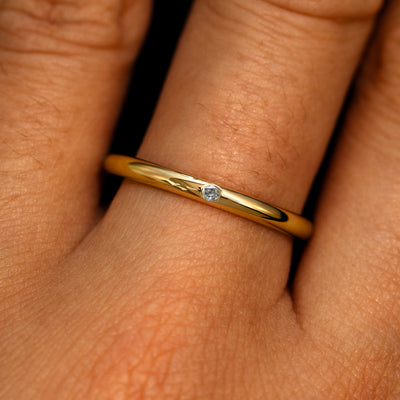 A 14k yellow gold Flush Set Sal and pepper Round Diamond Ring on a model's finger