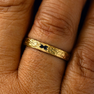 A black baguette diamond raw band on a models finger