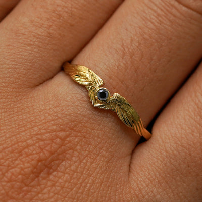 Close up view of a model's fingers wearing a 14k yellow gold Black Diamond Wings Ring