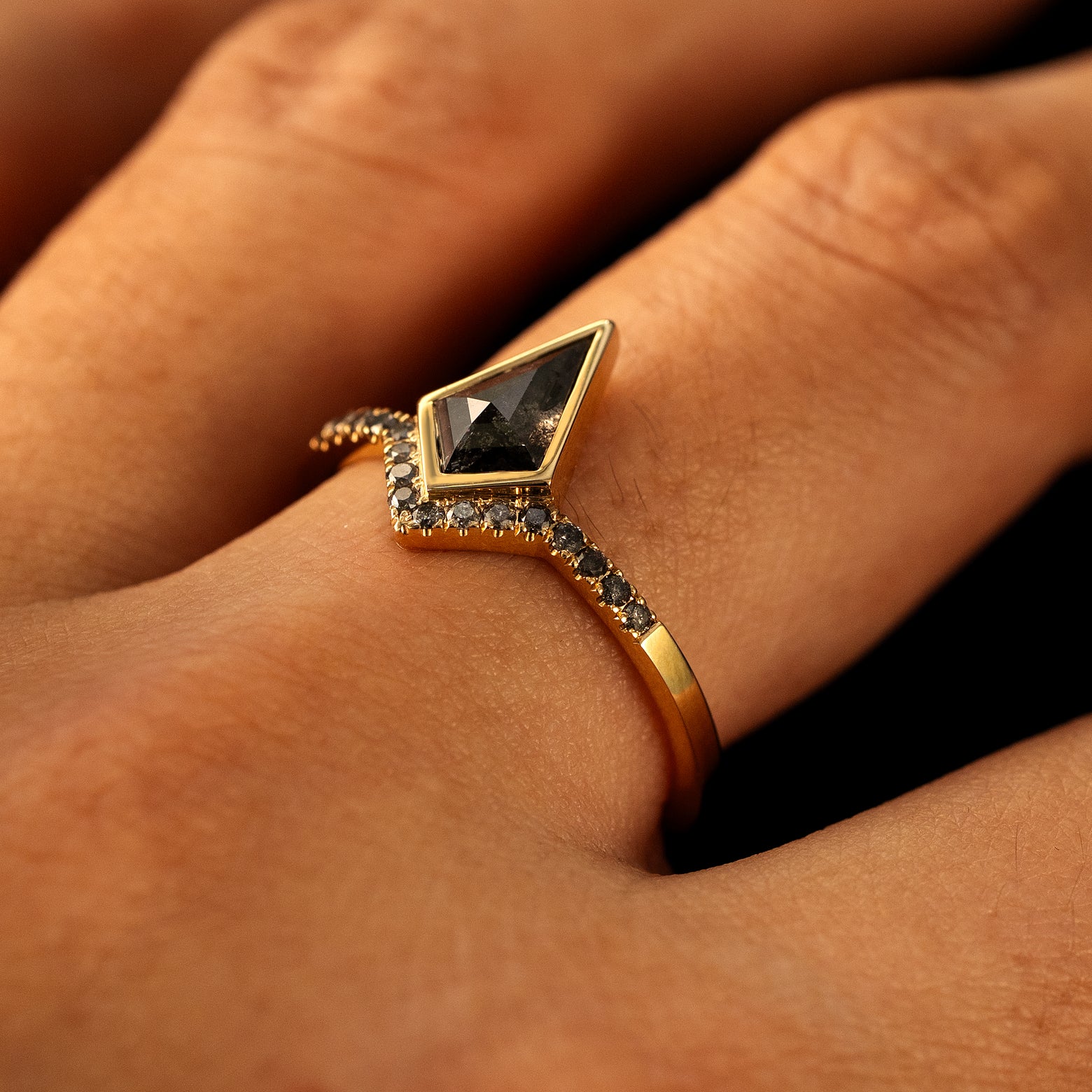 Side view of a solid 14 karat gold Kite Salt and Pepper Diamond Pave Chevron Ring on a model's finger