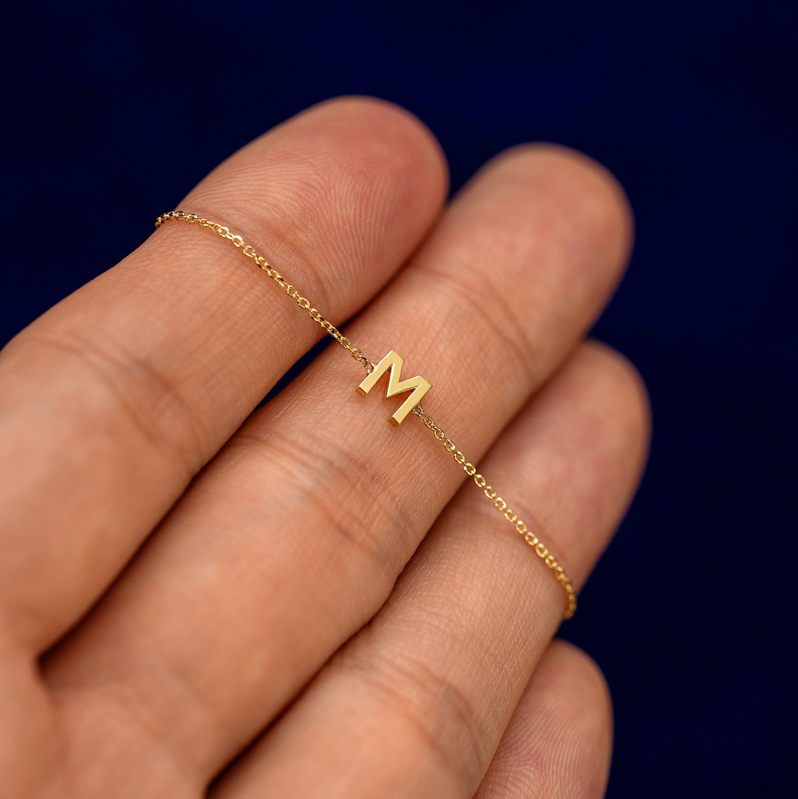 A model holding a block initial bracelet on their fingers to show the details of the chain