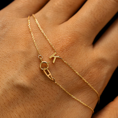 A letter K block initial cable chain necklace wrapped twice around a models hand