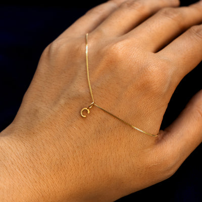 Close up view of a model's hand with a 14k gold letter C Initial Charm on a Mini Miami Chain