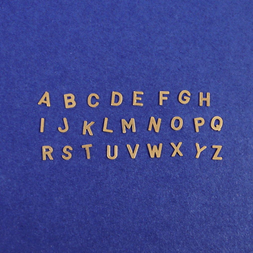 All twenty six block initials laying on a dark blue background