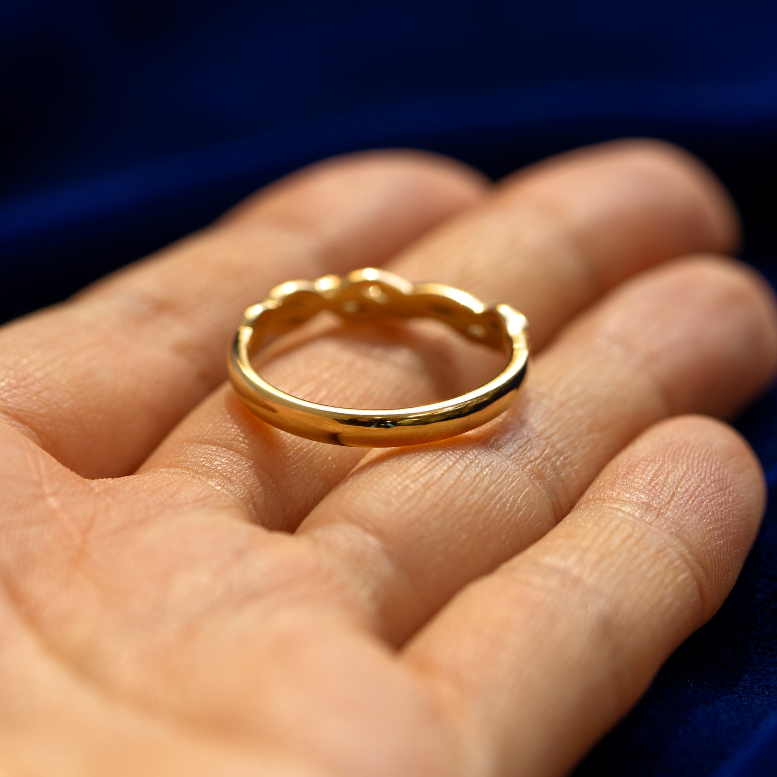 A yellow gold Braided Leaves and Vines Ring in a model's hand showing where the braid ends and the smooth band begins