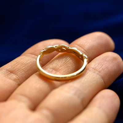 A yellow gold Braided Leaves and Vines Ring in a model's hand showing underneath the top of the ring