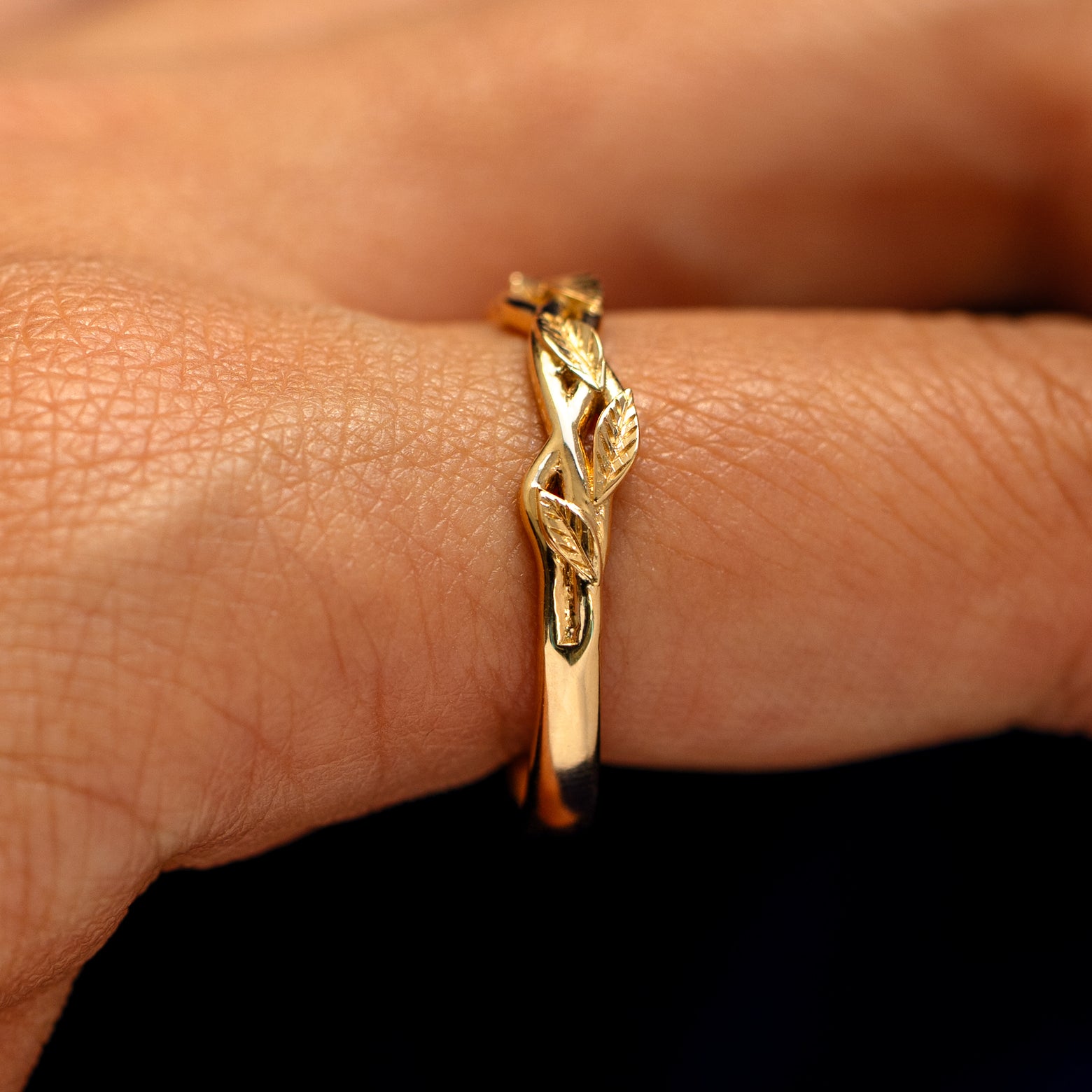 Side view of a Braided Leaves and Vines Ring on a model's finger to show the detailing of the braided vines and leaves