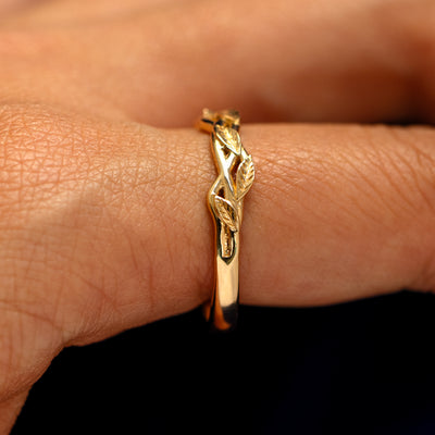 Side view of a Braided Leaves and Vines Ring on a model's finger to show the detailing of the braided vines and leaves