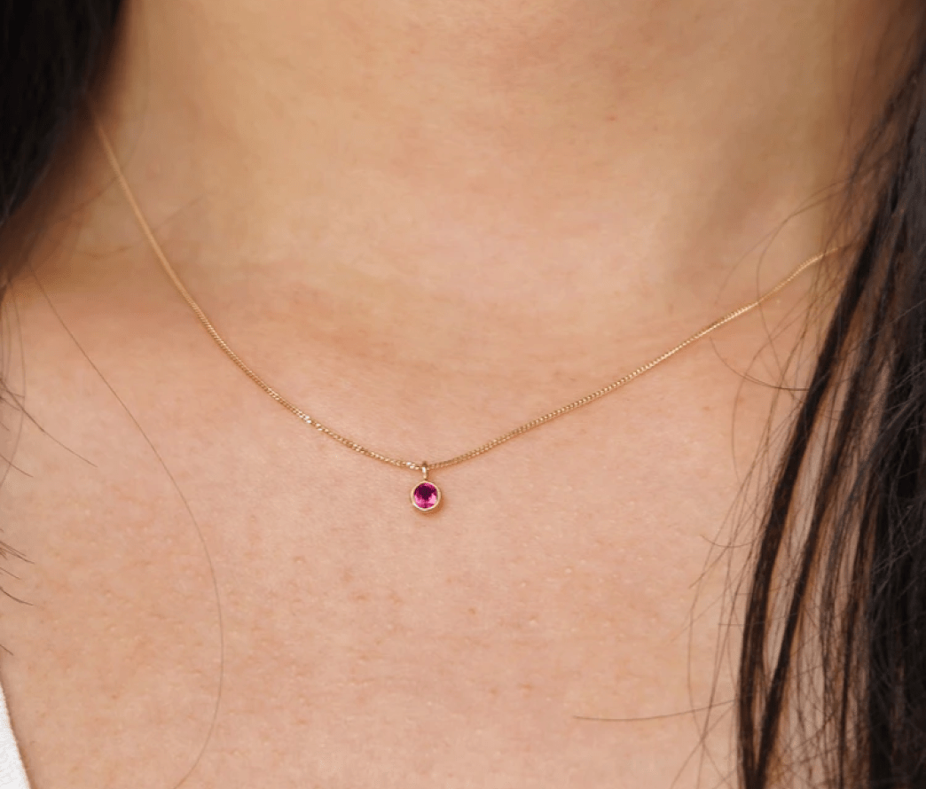Close up view of a model's neck wearing 14k yellow gold Ruby Necklace