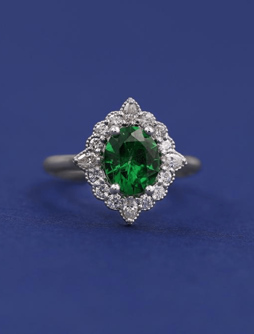 A custom engagement ring made from platinum featuring an oval tsavorite garnet surrounded by a milgrain set diamond halo