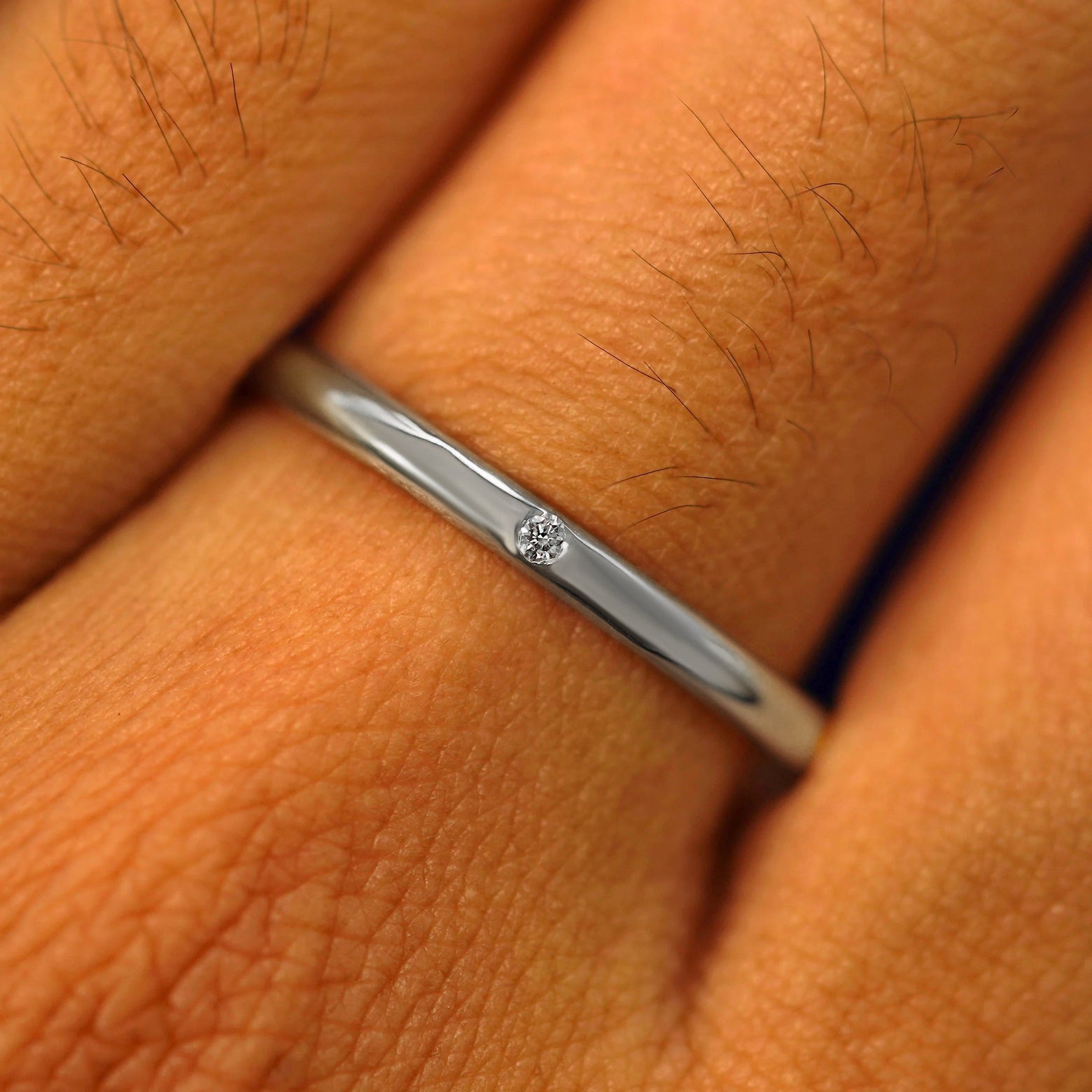Close up view of a model's fingers wearing a 4mm Silver Curvy Mirror Band with one diamonds