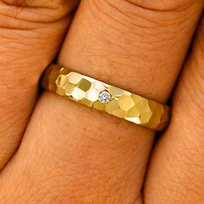 Close up view of a model's fingers wearing a yellow gold 2mm Curvy Hammered Band with center diamonds