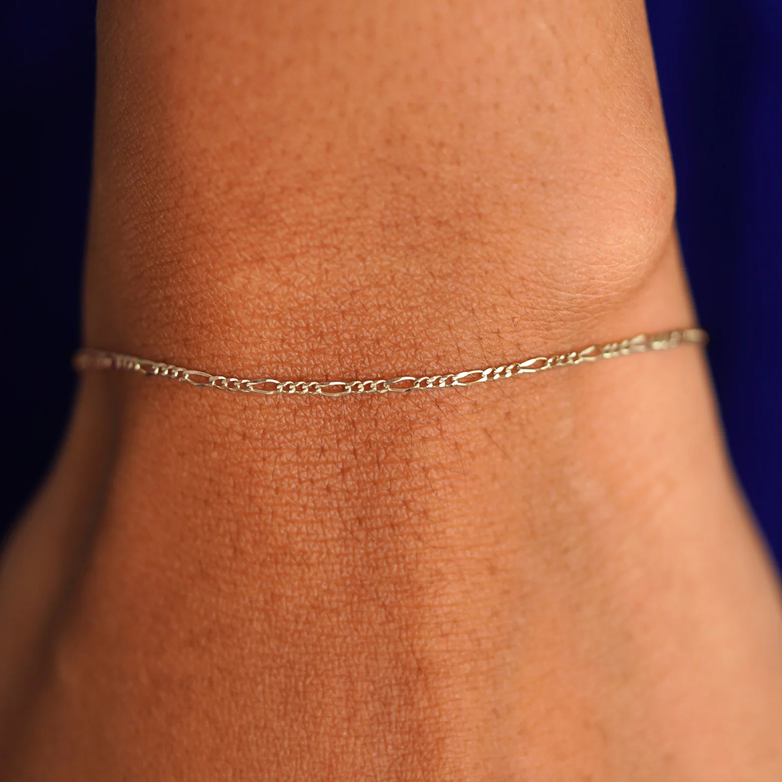 Close up view of a model's wrist wearing a solid champagne gold Figaro Bracelet