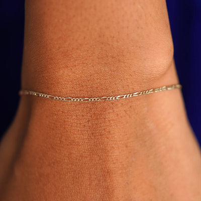 Close up view of a model's wrist wearing a solid champagne gold Figaro Bracelet