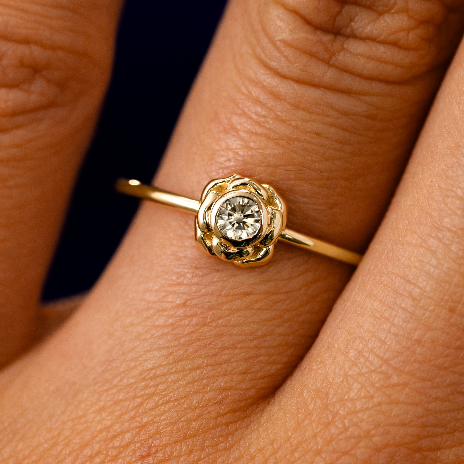 A solid 14k yellow gold Champagne Diamond Flower Ring on a model's finger
