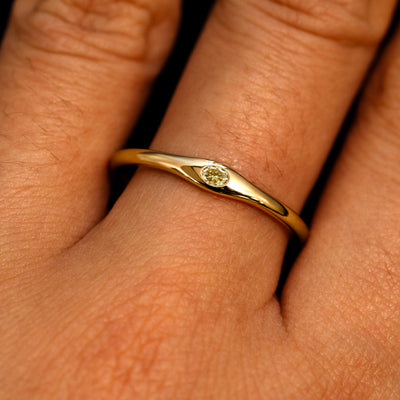 A 14k yellow gold Flush Set Oval Champagne Diamond Ring on a model's finger