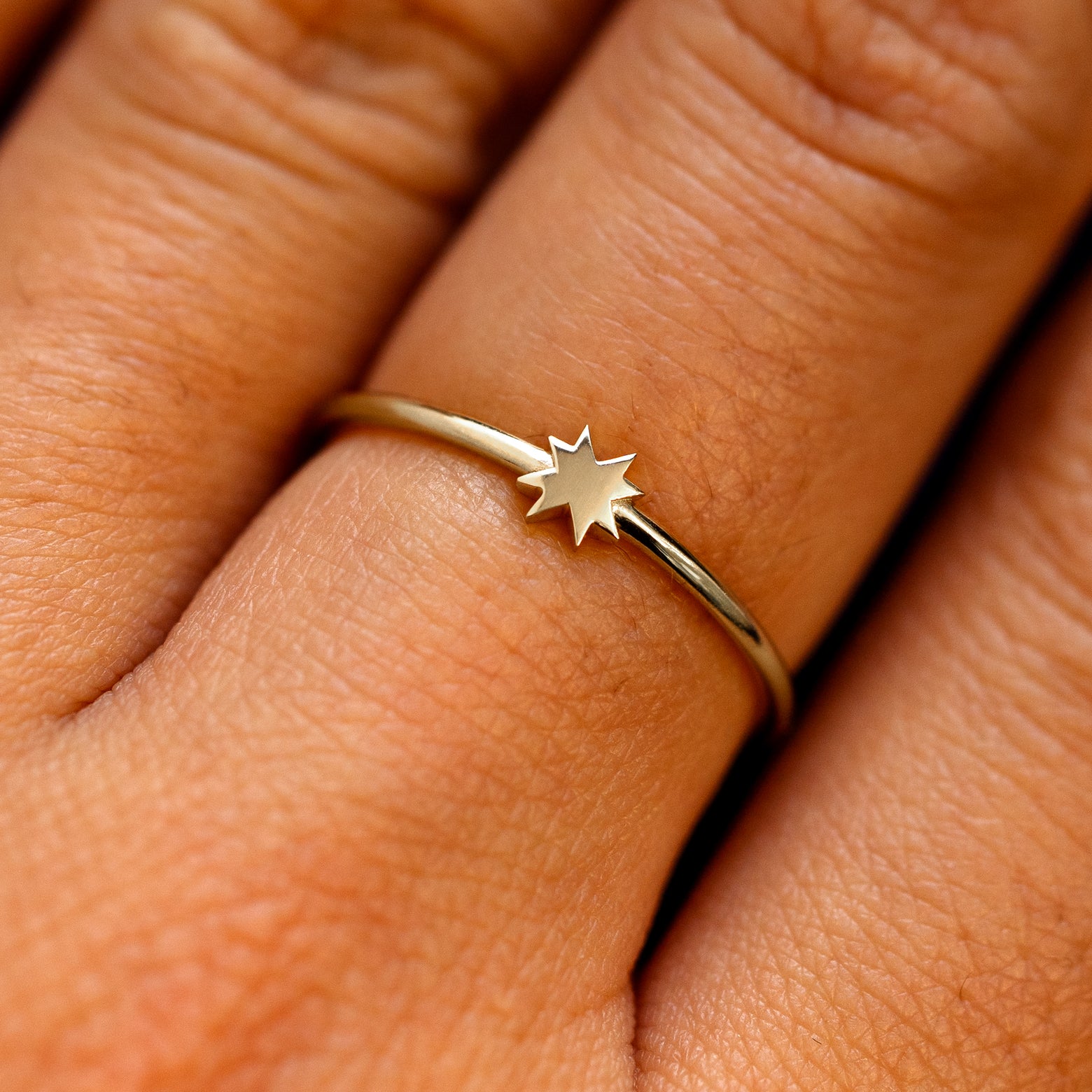 Close up view of a models fingers wearing a champagne gold 8 pointed star ring